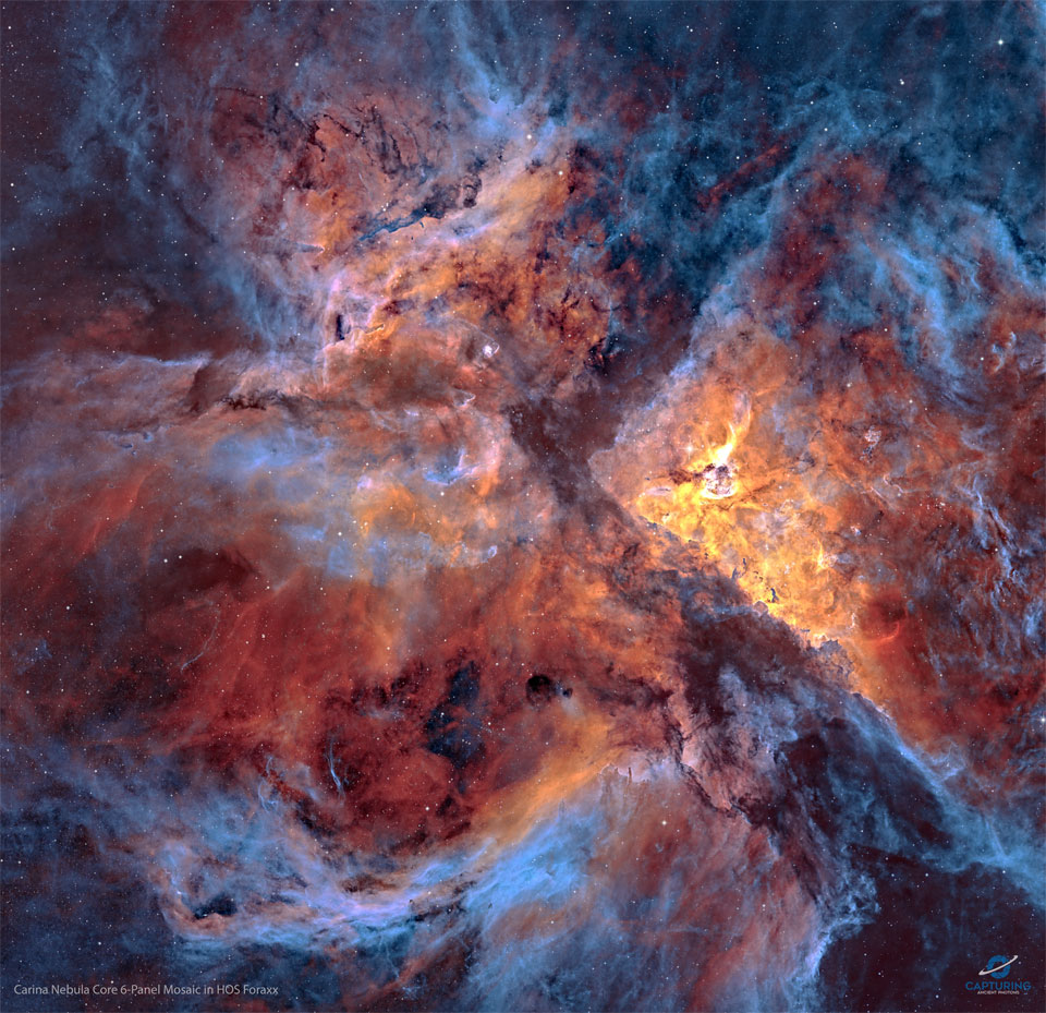 A star field strewn with filaments of dust and gas
is shown: the center of the Carina Nebula. Shown in 
colors emitted by specific elements, the frame shows
blue gas around the edges and orange and red colored
gas in the center. Dark dust laces the busy frame. 
Więcej szczegółowych informacji w opisie poniżej.
