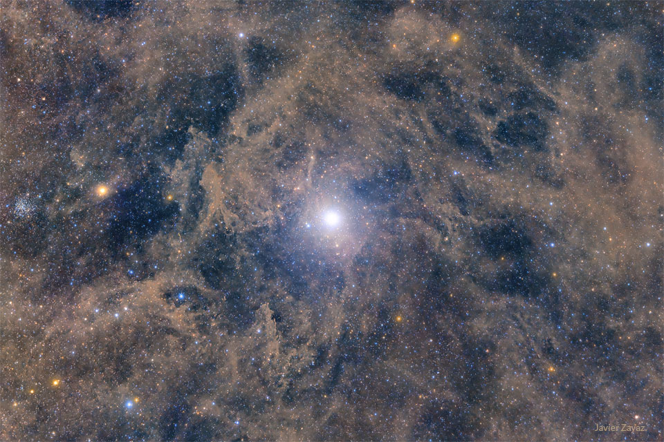 Jasna gwiazda widoczna w polu słabszych wraz z jasnobrązowym pyłem. Gwiazda to Polaris, Gwiazda Północy. Więcej szczegółów w opisie.