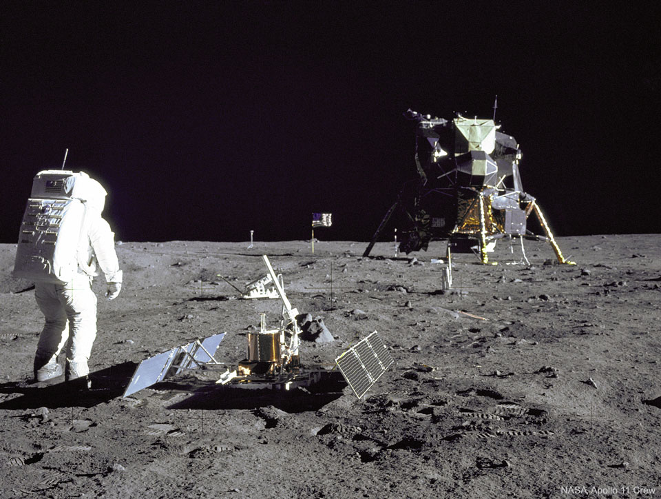 An astronaut is seen standing on the Moon next to 
an instrument with the lunar lander several meters in the 
distance. The dark of deep space covers the top of the frame. 
Więcej szczegółowych informacji w opisie poniżej.